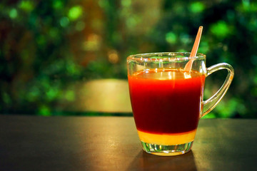Hot tea glass with a mixture of sweetened condensed milk and tea Put on the table at night Green forest background and beautiful light bokeh (Milk Tea, Gopi Ko Liang)