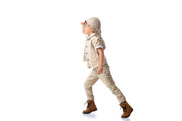 full length view of explorer boy in hat and glasses looking in distance on white