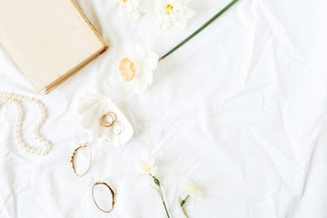 Minimal fashion French style composition with women's accessories: earrings, necklace, rings on white linen. Flat lay, top view.