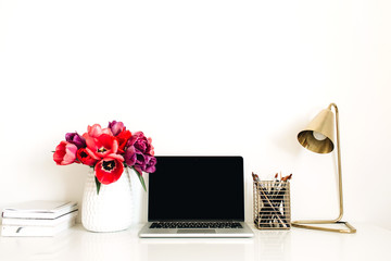 Home office workspace background with laptop, tulip flowers bouquet, stationery, lamp. Minimalist lady boss blog hero header with copy space template. Lifestyle still life concept.