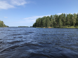 View from water level in a lake in Scandinavia. Canoes and small island in the distance. - 281605148