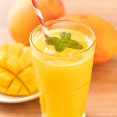 Fresh mango juice with beautiful chopped pulp flesh and straw on bright wooden table background. Tropical fruit design concept. Close up, copy space.