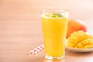 Fresh mango juice with beautiful chopped pulp flesh and straw on bright wooden table background. Tropical fruit design concept. Close up, copy space.