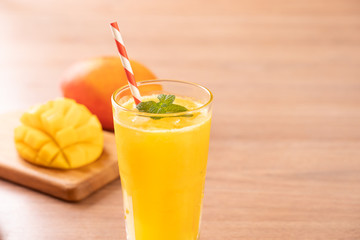 Fresh mango juice with beautiful chopped pulp flesh and straw on bright wooden table background. Tropical fruit design concept. Close up, copy space.
