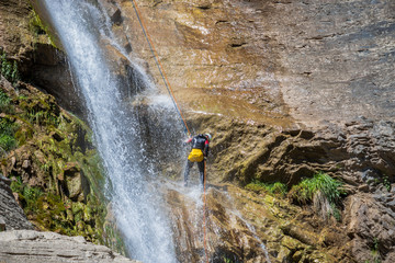 people rappelling in an impressive waterfall