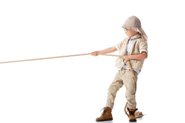 full length view of focused explorer kid in hat and glasses holding rope on white
