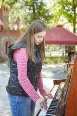 Girl with Down syndrome playing piano outdoors.