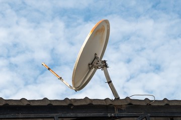 broken and old satellite dish on the roof and blue sky background.
