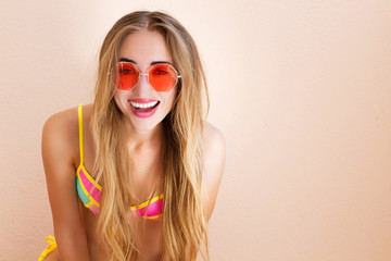 Close Up Of Happy Girl in pink sunglasses isolated. Summer holidays and fun time weekend. Summertime concept. Smiling young woman in fashion swimsuit. Selective focus. Beach Summer outfit. Copy Space
