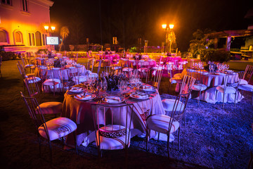 Served tables at the banquet in purple tones. Night photo.
