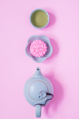Pink mooncake, blue teapot, cup of green tea on a pink background. Chinese mid-autumn festival food.