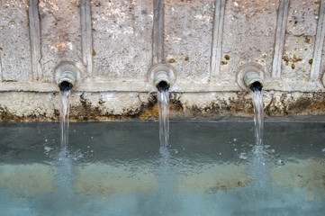 water falling from three pipes of a stone fountain. viewed closely