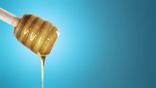 Honey dripping from honey dipper on blu background