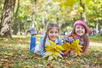 Girl with Down syndrome and little girl in autumn park.