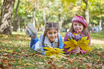 Girl with Down syndrome and little girl in autumn park.