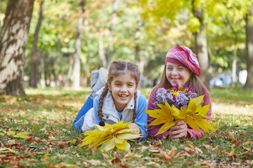 Girl with Down syndrome and little girl in autumn park.