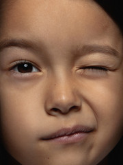 Close up portrait of little and emotional asian girl. Highly detail photoshot of female model with well-kept skin and bright facial expression. Concept of human emotions. Winking, smiling playful.