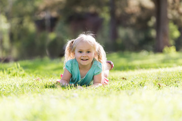 little girl on the grass smiling with blonde hair