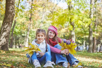 Girl with Down syndrome and little girl in autumn park.