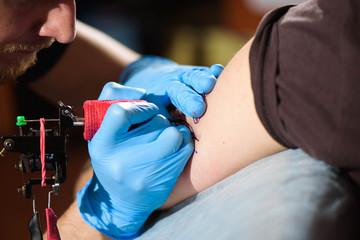 Tattoo artist creating a tattoo on a man's arm.