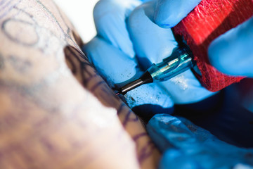 Master tattoo draws the black paint on the clients tattoo. Tattoo artist holding a tattoo machine...