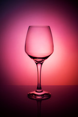 Wine glass on a purple red orange background.