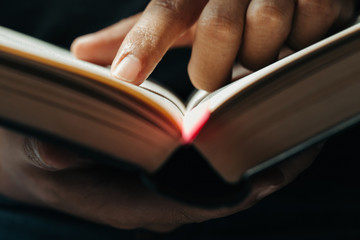 close-up of finger pointing text in Bible.close up of man reading through the Bible. - obrazy, fototapety, plakaty