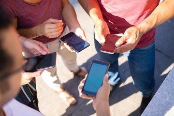 People standing in circle and using smartphones together. Men and woman holding mobile phones and exchanging data. Wireless connection concept