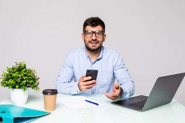 Smiling successful businessman in suit talking on phone using laptop sitting at office workplace