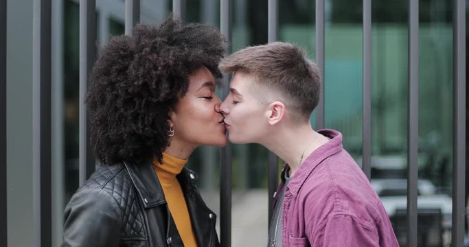 Young adult lesbian couple kissing outdoors in city