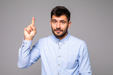 Attractive young man in blue t-shirt pointing up with his finger isolated on gray background