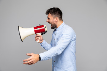 Side view of angry man shouting through megaphone against gray background