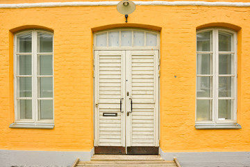 yellow brick house with large Windows and wooden door