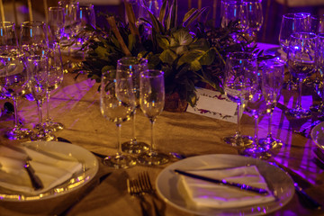 Served tables at the banquet in purple tones. Night photo.