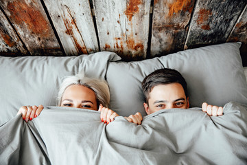 young lovely couple lying in a bed, happy smile