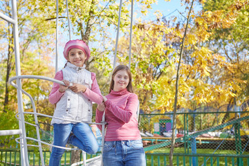 Fototapeta na wymiar Girl with Down syndrome and little girl in autumn park.