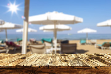 Table top background with a sunny sandy beach and sun beds and umbrellas. Empty space for advertising product and decoration.