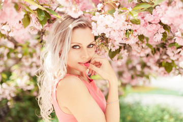 Obraz na płótnie Canvas Beautiful blonde in a pink dress near a flowering tree