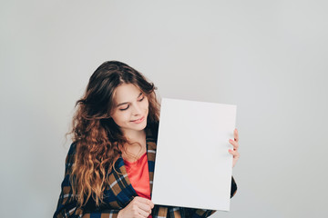 Girl holding a blank empty canvas board in her hands and smiling. Copy space. European young woman...