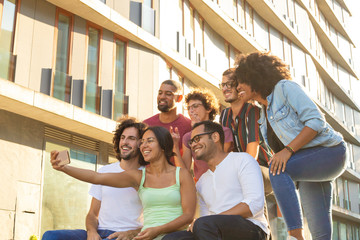 Joyous happy multiethnic friends taking group selfie outside. Interracial men and women posing and laughing at phone camera. Friends concept