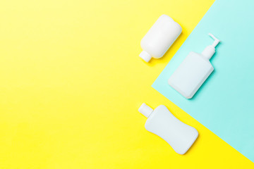 Set of White Cosmetic containers isolated on yellow and blue background, top view with copy space. Group of plastic bodycare bottle containers with empty space for you design