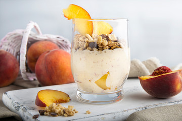 Healthy peach yogurt in a glass on a rustic white wood background