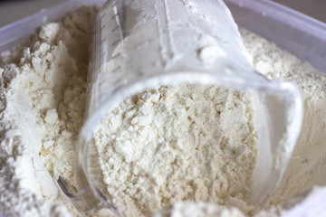 Flour with Measuring Cup in Container. Flour in a measuring Cup. Flour in container. Flour in a container with a measuring Cup