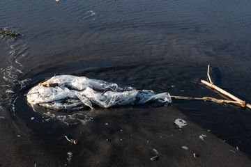 Waste plastic bag on the water surface on a beach. Garbage on the beach.