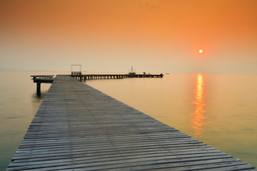 Obraz na płótnie Canvas Wooden bridge that stretches into the sea at sunrise.