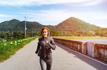 Women wearing running suits and wearing headphones, running in the morning.Women wearing headphones with music on the phone, exercise
