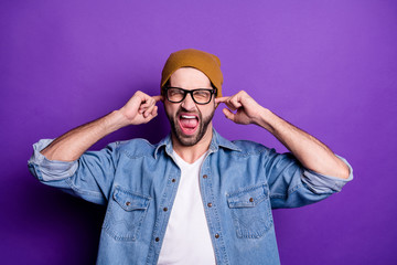 Portrait of his he nice attractive fury aggressive crazy bearded guy closing ears with fingers screaming isolated over bright vivid shine violet lilac background