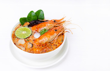 Tom Yum Goong or Shrimp soup spicy sour Soup Traditional food in Thailand contains chili, lime, ginger, galangal, lemongrass, lime leaf, from top view on a white wood background.