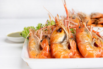 Burned shrimp Or Grilled shrimp and seafood sauce is very tasty on a white plate on white wood background.