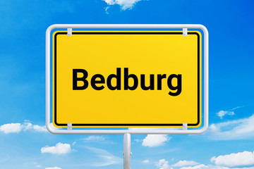 Obraz premium Stadt Bedburg. Gelbes Schild, Ortsschild, Ortseingangsschild. Himmel mit Wolken.